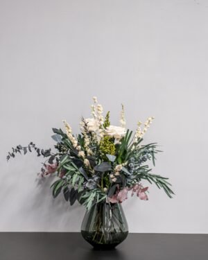 En elegant torkad blombukett med vita rosor och eucalyptus i en stilren vas som skapar en harmonisk inredning.