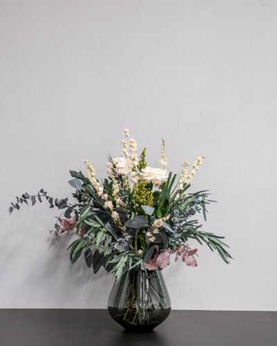 En elegant torkad blombukett med vita rosor och eucalyptus i en stilren vas som skapar en harmonisk inredning.